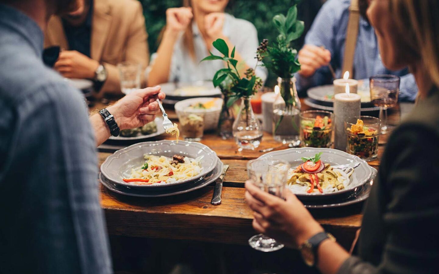 group of people sitting at an outdoor restaurant table eating and socializing