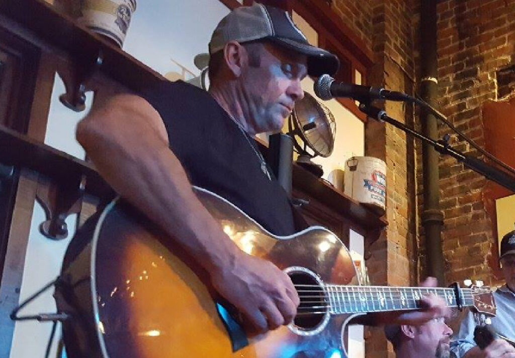 man standing in front of a mike playing guitar